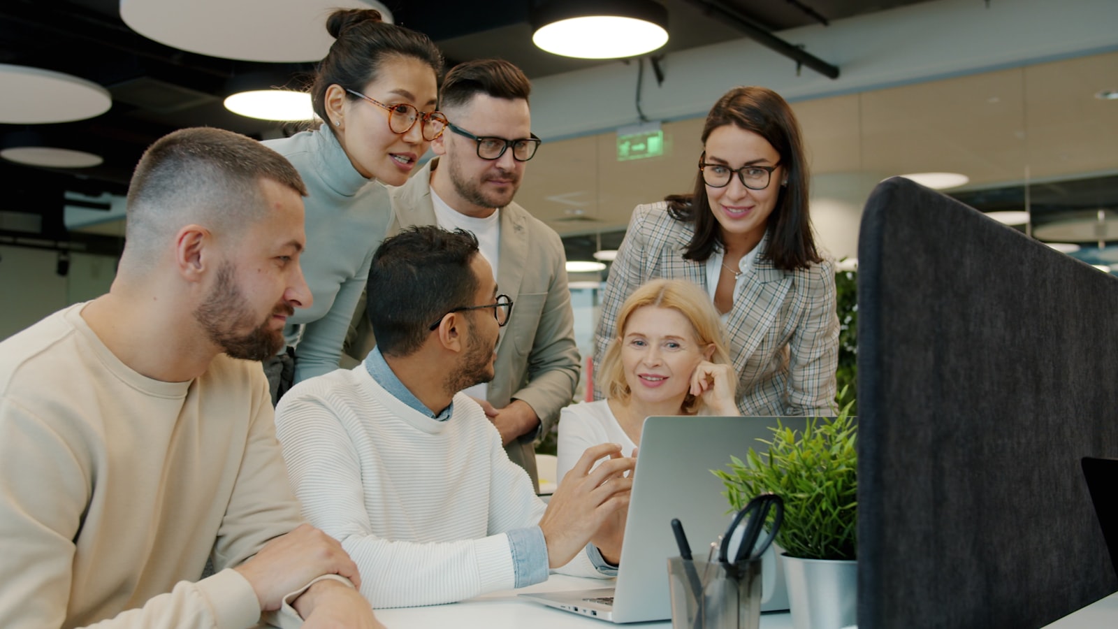 A marketing and operations team reviewing campaign work together around laptops.